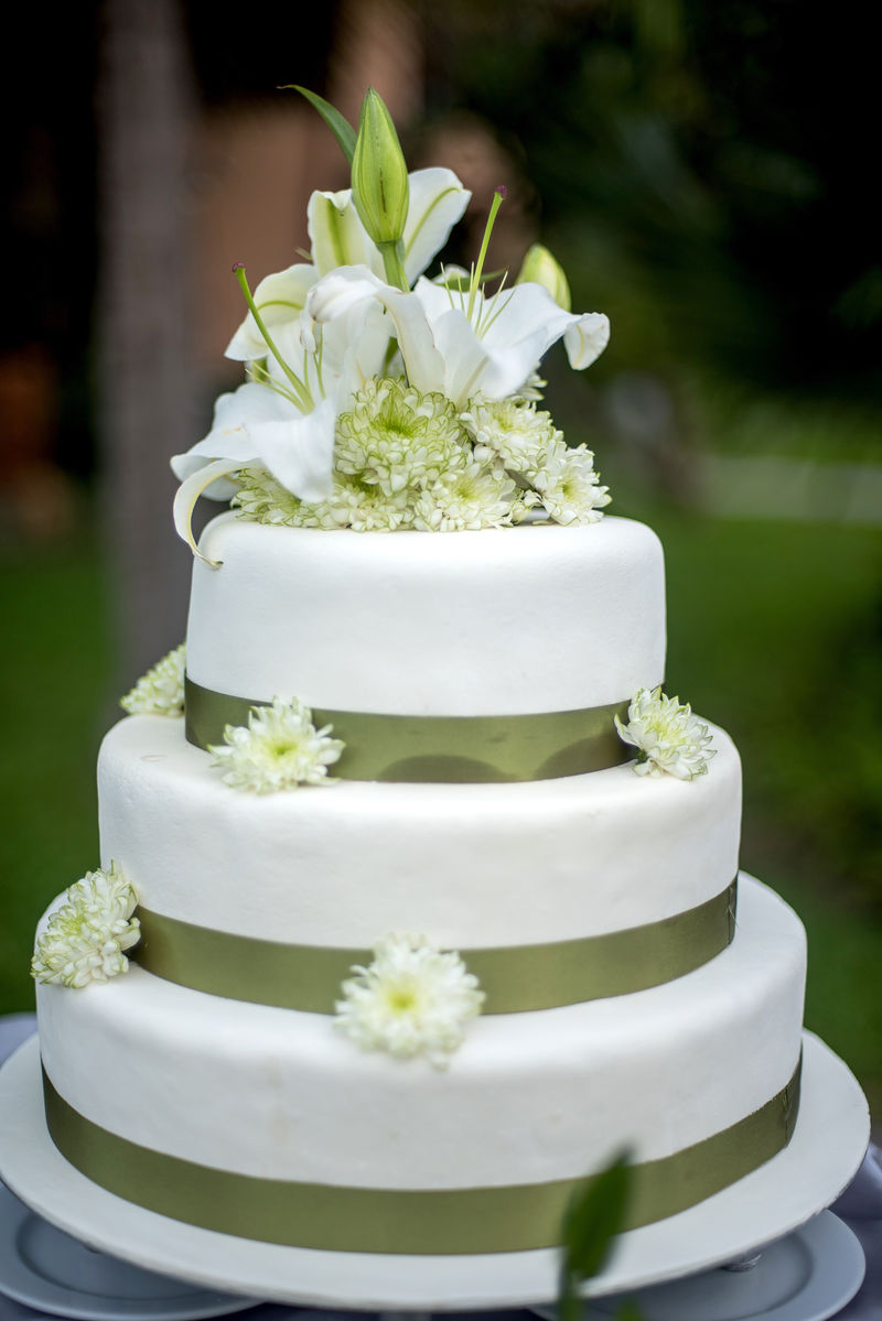 Natural garden-style wedding cake with white lilies and olive ribbons